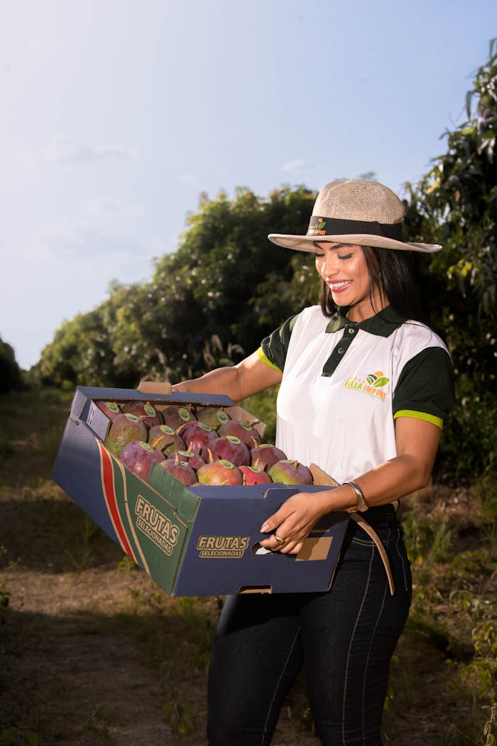 services-02 A happy farmer carrying a box of fresh organic mangoes outdoors.